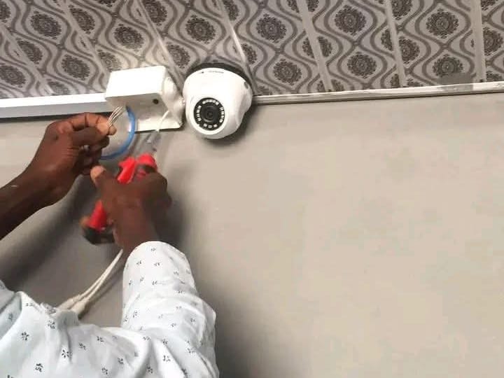 A technician connecting the cable of a dome camera at ceiling height
