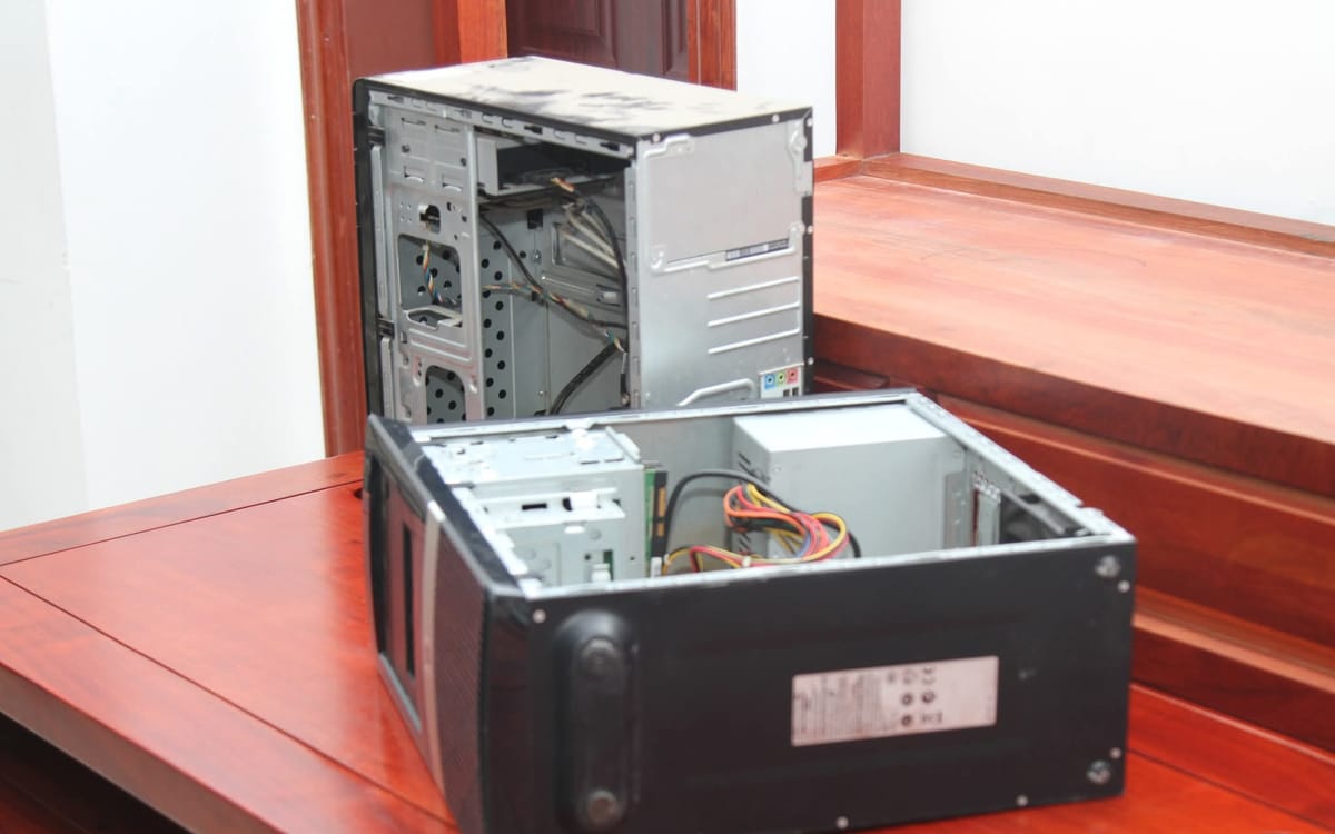 Two desktop computers opened on a bench for repair, with the power supply and drive bays visible